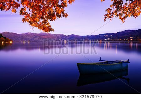 Evening Autumn Mood With A Blue Tint On The Lake With A Boat. Kastoria, Greece.