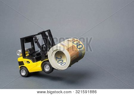 A Yellow Loader Stands On The Rear Wheels Holding A Big Roll Bundle Of Euro. Concept Of Attracting I