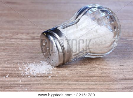Glas saltcellar med salt på træ baggrund