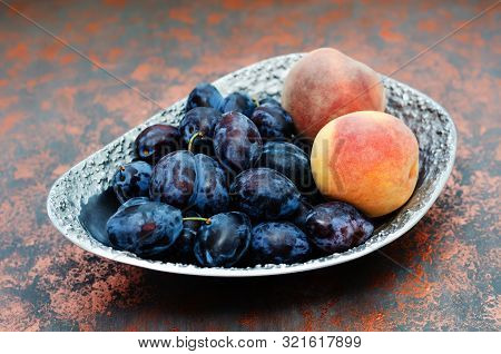 Fresh Organic Plums And Peaches In A Metal Vase On The Bronze Shagreen Background. Still Life Of Rip