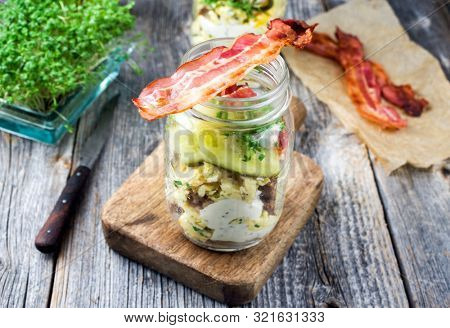 Brotzeit im Glas â traditional Bavarian snack with ham, eggs and black bread in a glass as closeup on a wooden board 