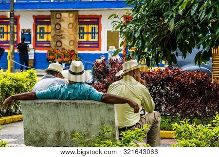 People Of Colombia, Group Of Old Man Sitting On Bench In The Colorful Streets Of Filandia Village