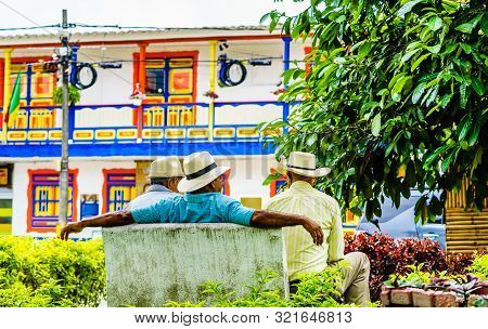 People Of Colombia, Group Of Old Man Sitting On Bench In The Colorful Streets Of Filandia Village
