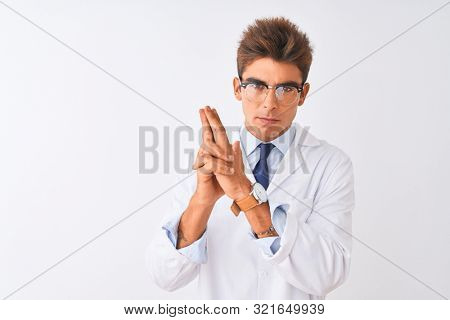 Young handsome sciencist man wearing glasses and coat over isolated white background Holding symbolic gun with hand gesture, playing killing shooting weapons, angry face