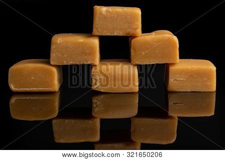 Group Of Six Whole Sweet Golden Caramel Candy In Pyramid Isolated On Black Glass