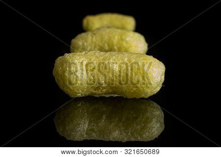 Group Of Three Whole Salted Yellow Corn Puff Isolated On Black Glass