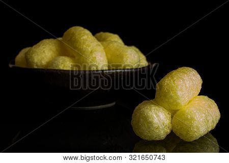 Lot Of Whole Salted Yellow Corn Puff In Dark Ceramic Bowl Isolated On Black Glass