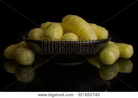 Lot Of Whole Salted Yellow Corn Puff In Dark Ceramic Bowl Isolated On Black Glass