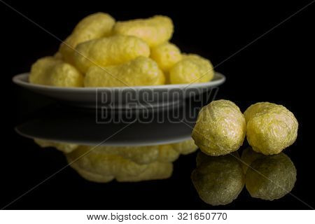 Lot Of Whole Salted Yellow Corn Puff On White Ceramic Plate Isolated On Black Glass