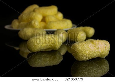 Lot Of Whole Salted Yellow Corn Puff On White Ceramic Plate Isolated On Black Glass