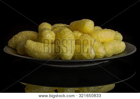Lot Of Whole Salted Yellow Corn Puff On Gray Ceramic Plate Isolated On Black Glass