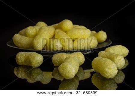 Lot Of Whole Salted Yellow Corn Puff On Gray Ceramic Plate Isolated On Black Glass