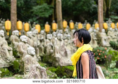 traveling modern Asian woman at a garden with arhat stone statues