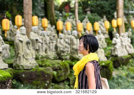 traveling modern Asian woman at a garden with arhat stone statues