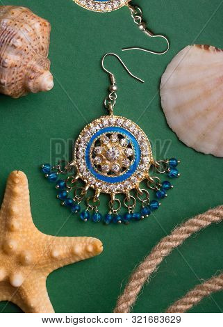 Earrings Decorated With Precious Stones Lying On The Background Of Seashells. Concept Nautical Decor