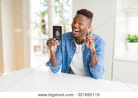African american man holding passport of Canada surprised with an idea or question pointing finger with happy face, number one