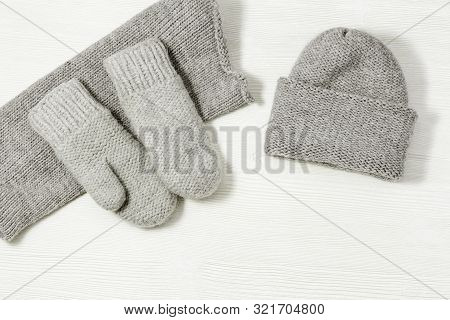 Woolen Knitted Clothing, Wool Cap, Mittens And Scarf. Warm Womans Winter Clothes On White Wooden Bac