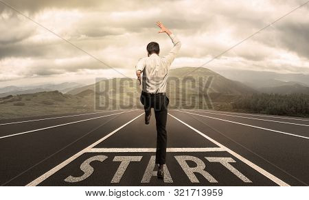 Businessman Jumping On A Starting Grid With The Meadow On The Background. Caucasian Man, Empoyer In 