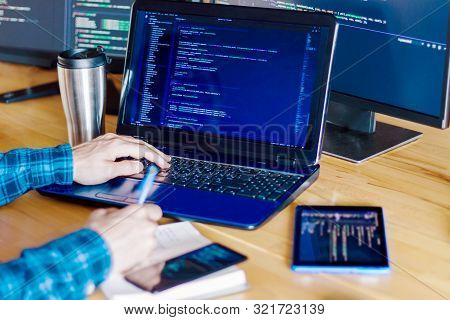 Multiple Computer Screens With Program Code On Office Table. Programmer, Developer Hands Are Typing 
