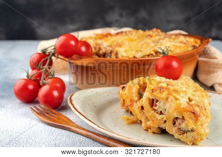 Golden Cannelloni With Meat, Tomatoes, Cheese Sauce And Pasta In Alternating Layers On A Rustic Plat