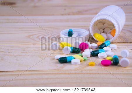 Assorted Pharmaceutical Medicine Pills, Tablets And Capsules And Bottle On Wooden Table Background.