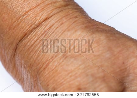Senior Woman's Wrinkled Wrist Of The Arm On White Background, Close Up & Macro Shot, Selective Focus