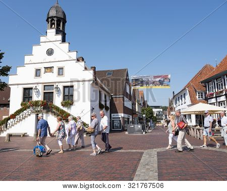 Lingen, Germany, 27 August 2019: Senior Tourists Pass Old Town Hall On Market Square In German Town 