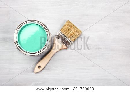 Copyspace With Paintbrush And Can With Green Paint Lying On White Wooden Clean Table. Top View. Copy