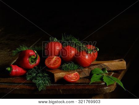 Tomatoes And Peppers With Herbs On The Table. Still Life.