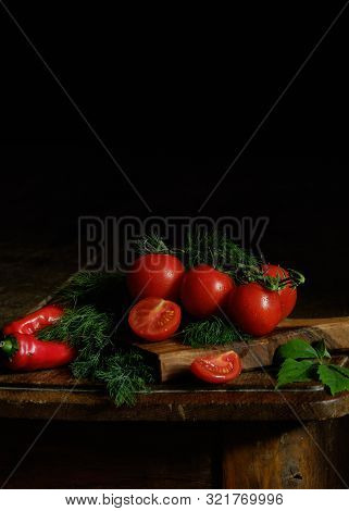 Tomatoes And Peppers Along With Herbs On A Wooden Board.