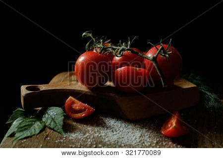 Still Life. Tomatoes And Dill  On A Table On A Black Background. Tomatoes Sprinkled With Salt