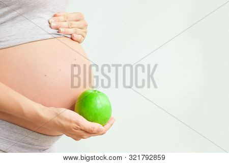 Pregnant Girl Holding A Green Apple. Nutrition During Pregnancy. Vitamins And Pregnancy. Source Of I