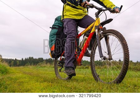 Close-up Of A Tourist Bike With A Saddlebag Riding Across The Field On A Cloudy Afternoon In The Cou