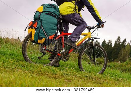 Close-up Of A Tourist Bike With A Saddlebag Riding Across The Field On A Cloudy Afternoon In The Cou