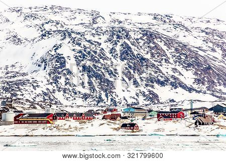 Arctic City Panorama With Colorful Inuit Cottages And Oil Factory On The Rocky Hills Covered In Snow