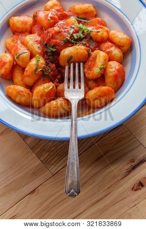 Italian Gnocchi In Red Marinara Tomato Sauce With Basil On Wooden Kitchen Table