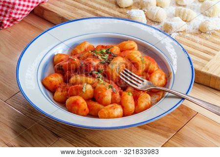 Italian Gnocchi In Red Marinara Tomato Sauce With Basil On Wooden Kitchen Table