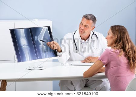 Doctor Showing Knee X-ray To Patient On Computer Screen