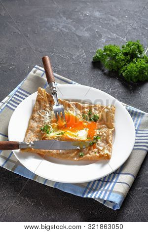 Breton Crepe, Savory Buckwheat Galettes Bretonnes With Spilled Egg, Cheese, Ham On A White Plate On 