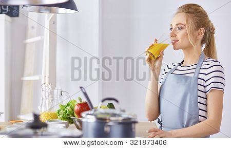 The Girl At The Table In The Kitchen With A Glass Of Orange Jui