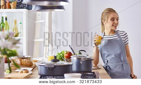 The Girl At The Table In The Kitchen With A Glass Of Orange Jui