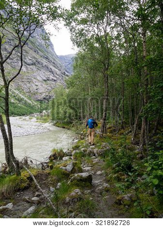 An Indefinite Man With Tourist Equipment Is Walking Over Stones In A Forest In Norway. Hiking Trail 
