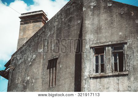 Bottom View Of The Facade Of An Abandoned Antique Building With Grey Concrete Grungy Walls, Window H