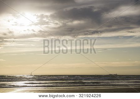 Sunset At La Barrosa Beach In Sancti Petri, Cadiz, With Sailboat Sailing Towards The Castle