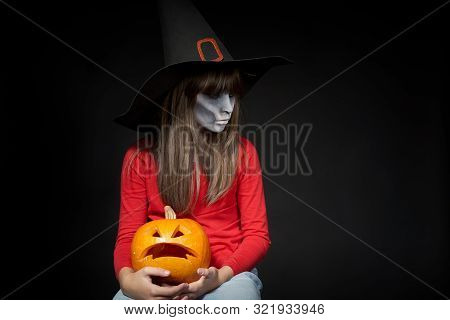 Serious Halloween Witch Holding Jack Olantern Pumpkin Looking At Camera