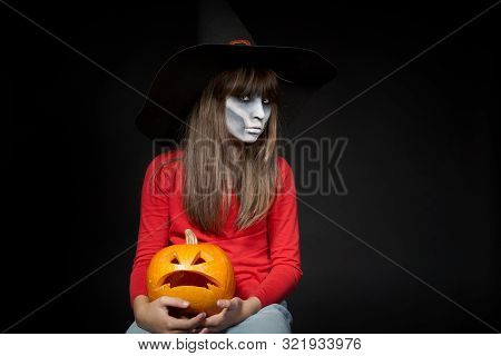 Serious Halloween Witch Holding Jack Olantern Pumpkin Looking At Camera