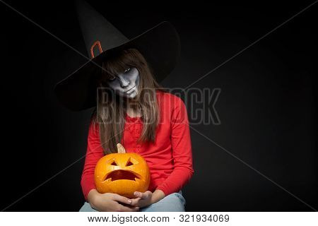 Serious Halloween Witch Holding Jack Olantern Pumpkin Looking At Camera