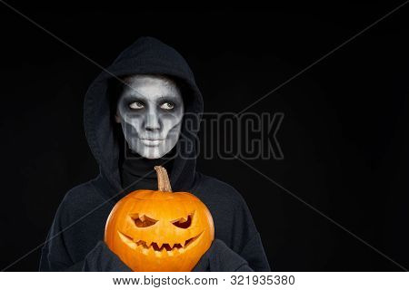 Boy With Halloween Makeup Holding Jack Olantern Pumpkin On Black Background