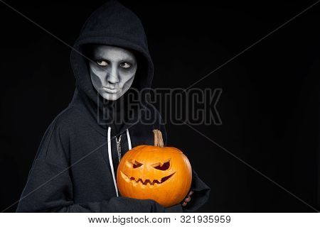 Boy With Halloween Makeup Holding Jack Olantern Pumpkin On Black Background