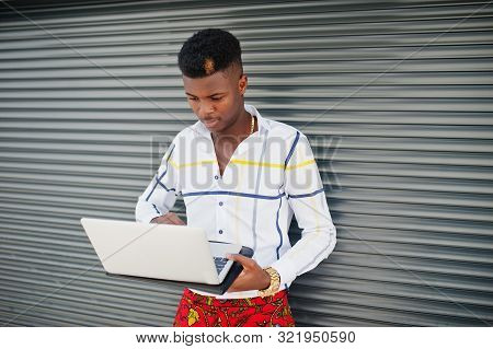 Portrait Of Handsome Stylish African American Model Man In Red Throusers And White Shirt With Laptop